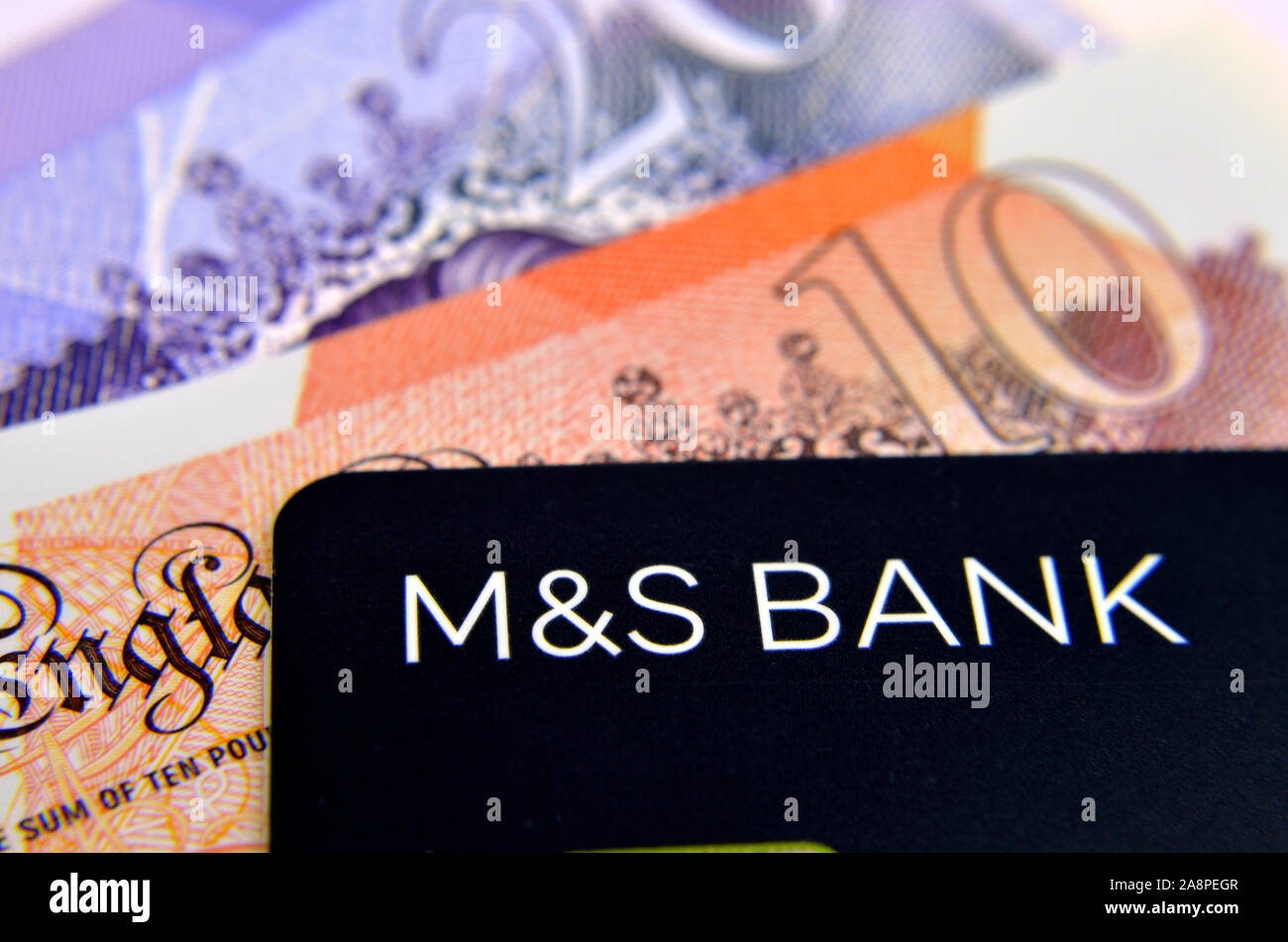 M&S bank credit card and blurred cash at the background. Photo with selective focus. Stock Photo