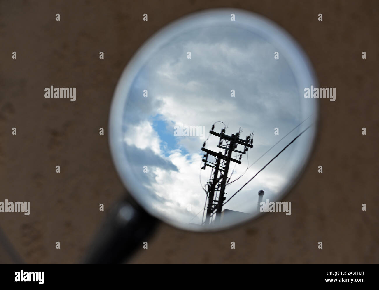 Electricity pylon as seen through the mirror of a motorbike. Concept : Electricity consumption & production. Stock Photo