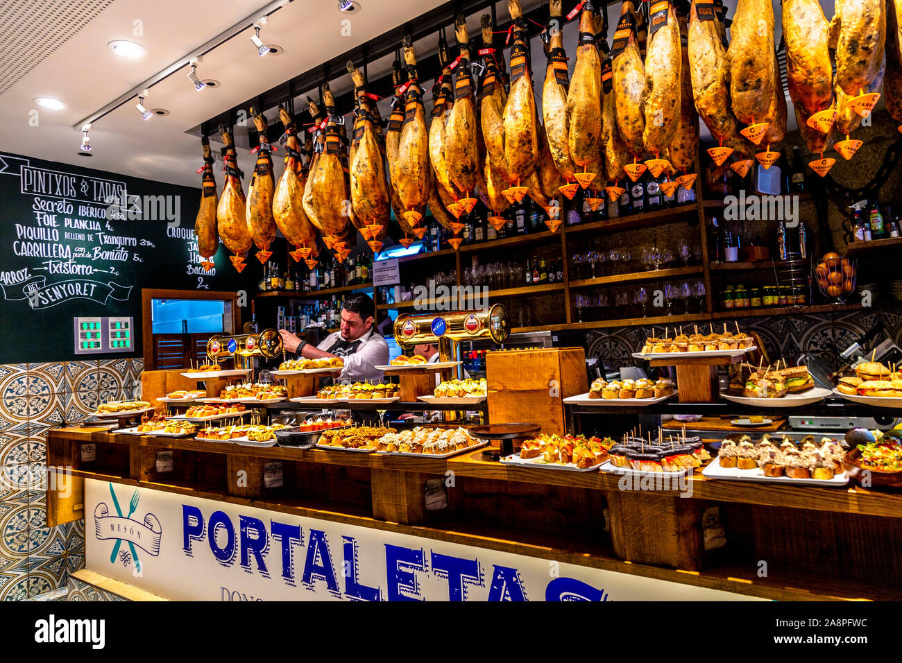 Iberian ham hanging over the counter of pintxos bar Meson Portaletas, San Sebastian, Spain Stock Photo