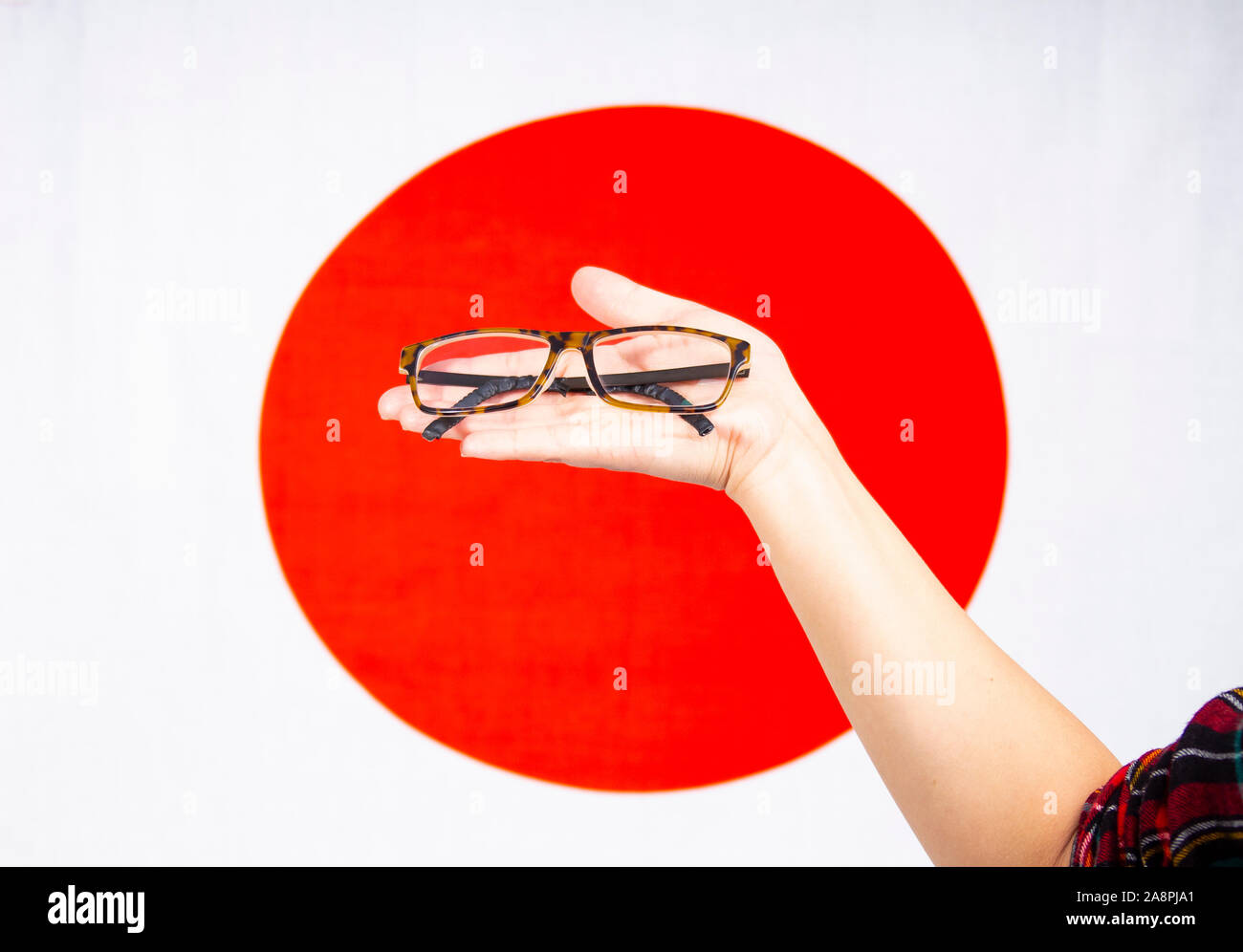 Female hand holding a pair of glasses with a japan flag Stock Photo