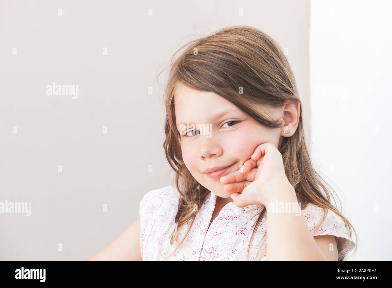 Smiling little Caucasian girl, close-up face portrait over gray wall background Stock Photo