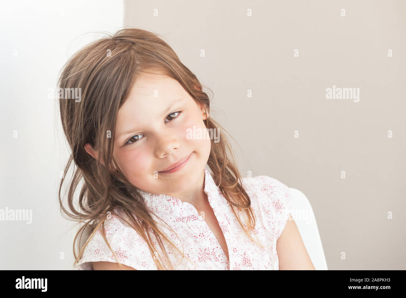 Smiling little blond Caucasian girl, close-up face portrait over gray wall background Stock Photo