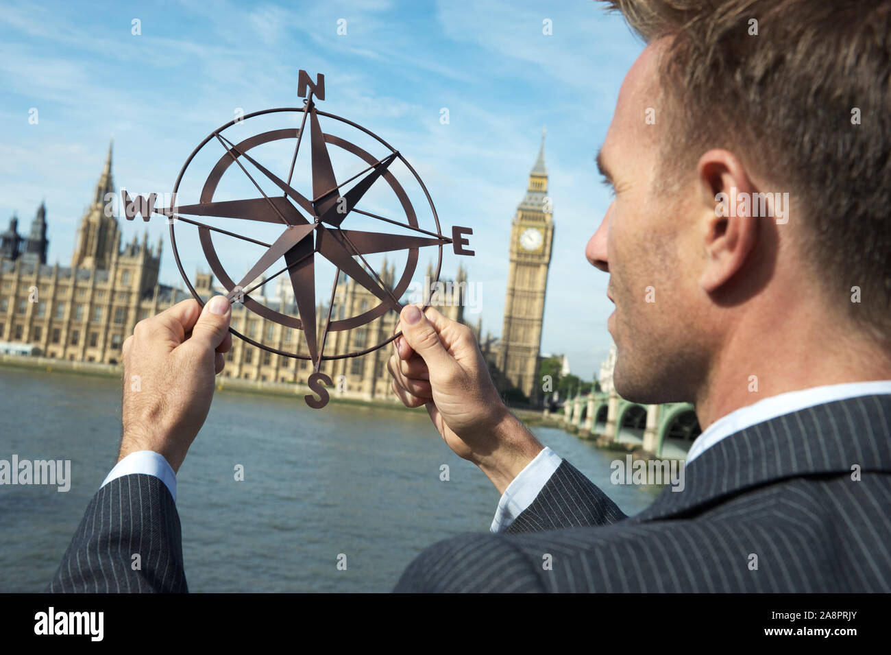 Businessman holding old-fashioned compass rose in front of the Houses of Parliament, London, UK Stock Photo
