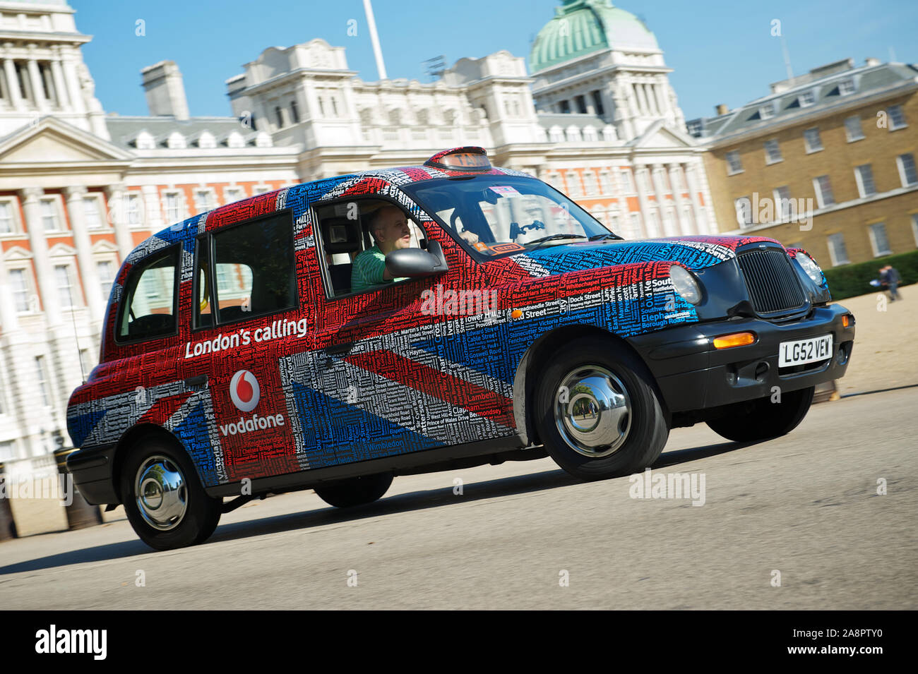 LONDON - OCTOBER 14, 2011: Traditional English black cab wrapped in patriotic advertising drives in front of Horse Guards Parade, Stock Photo