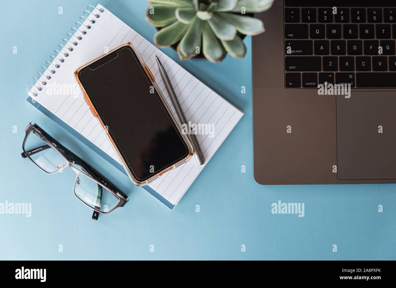 Overhead view of workspace with laptop, phone, glasses and notepad ...