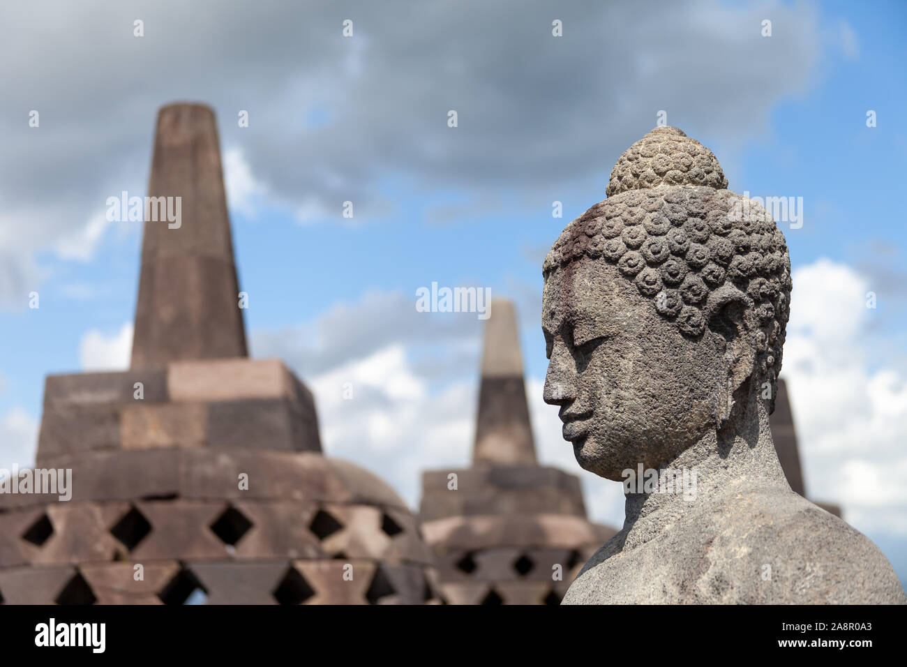 A Buddah in his stupa of Borobodur overlooking the surrounding land and watching over the volcanoes. Some of them are opened during dry season. A stun Stock Photo