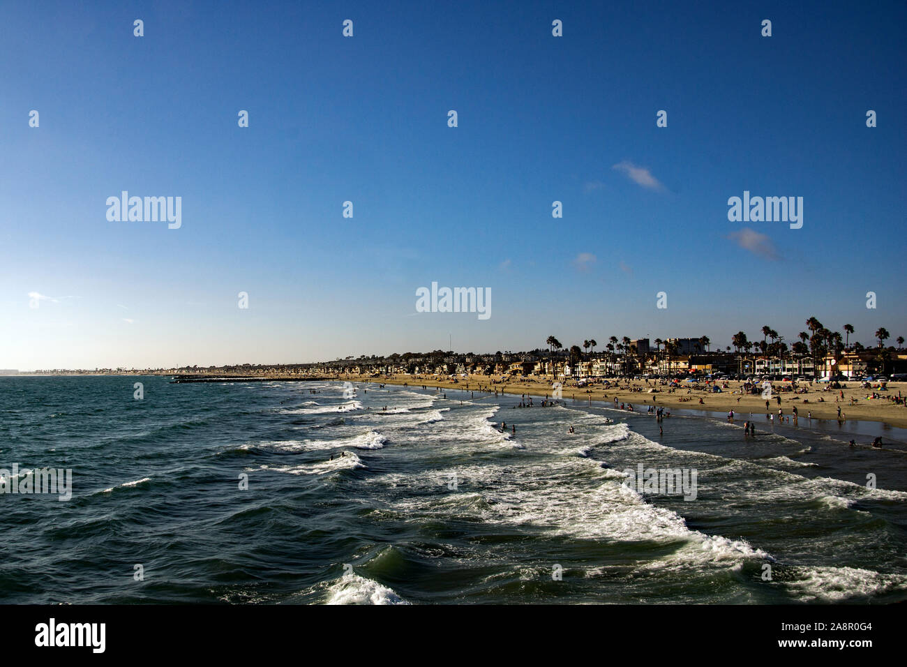 Waves hitting the beach T Newport in California, packed with holidaymakers. Stock Photo