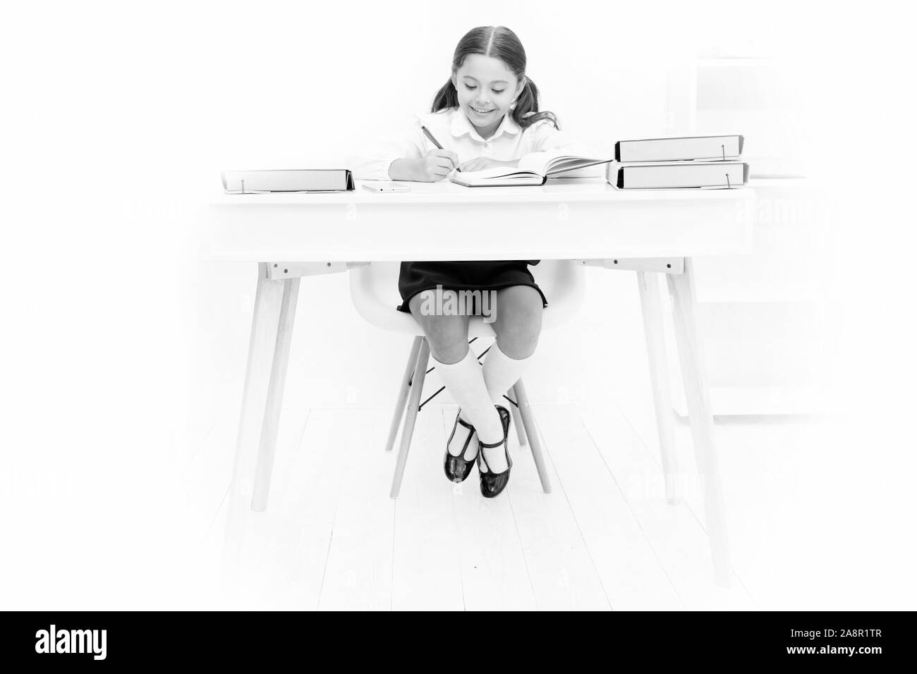 What should be height of study table. Schoolgirl doing homework at table. Adorable pupil little girl studying at table white background. Studying on desk with incorrect height can lead back pain. Stock Photo