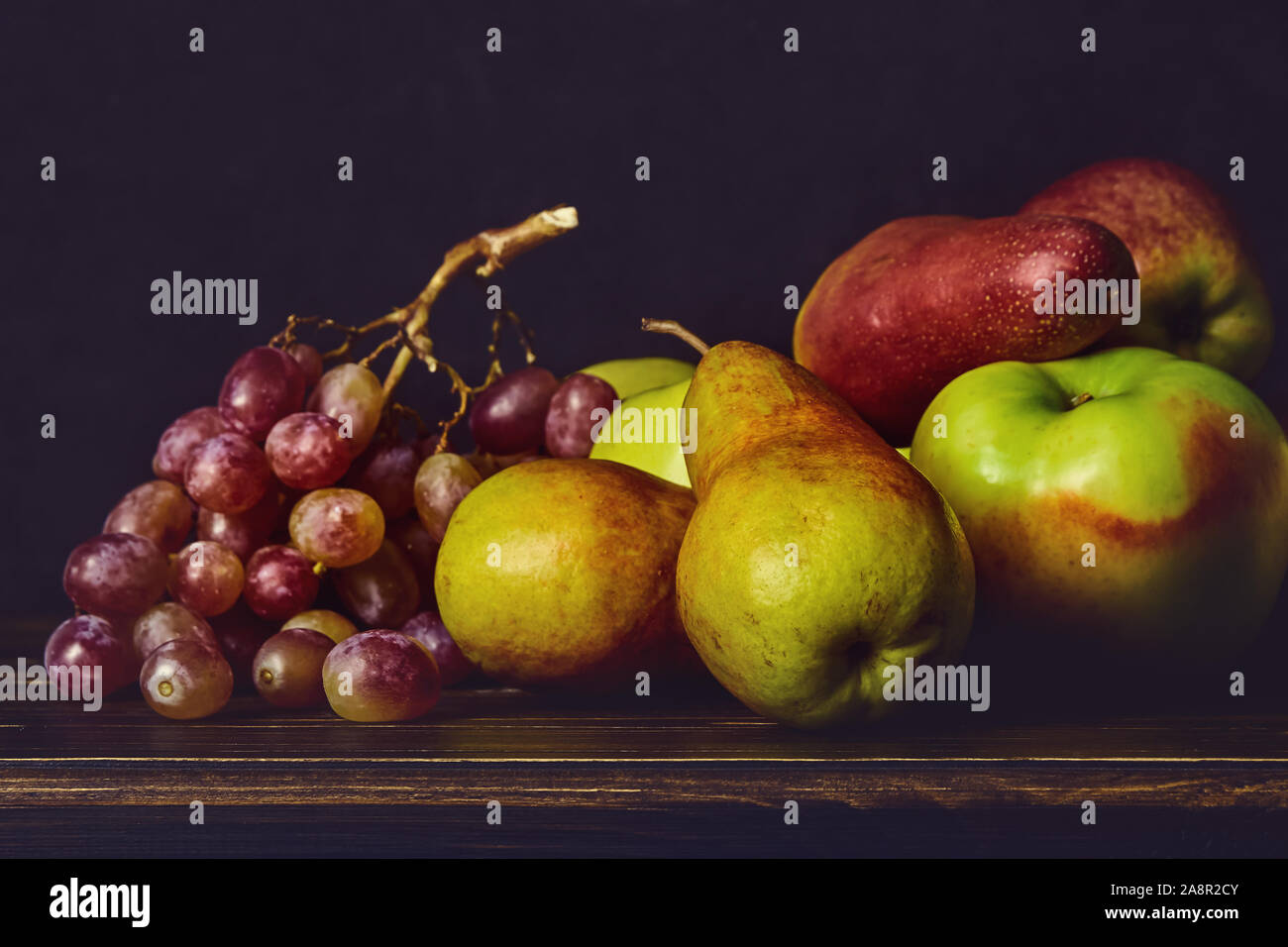 Ripe fruits, apples, pears grapes on a wooden old table and dark background. Fruit still life Stock Photo