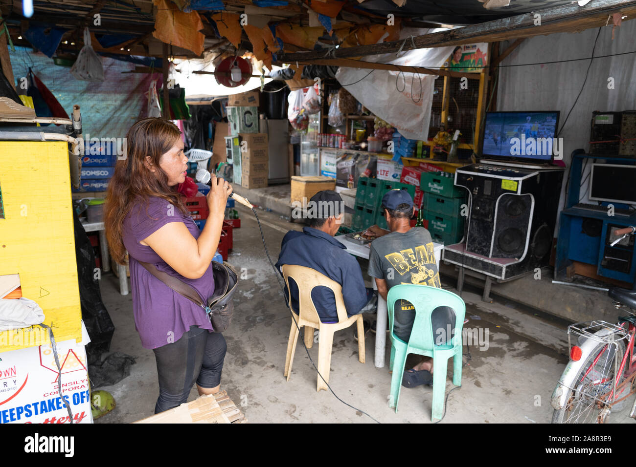 Karaoke singing is a major part of Filipino lifestyle.Karaoke booths can be found almost everywhere in the Philippines.Here a woman sings during a Sun Stock Photo