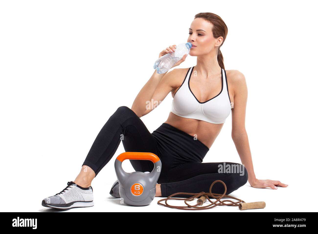 Woman drinking water from bottle after workout, isolated on white, hydration Stock Photo