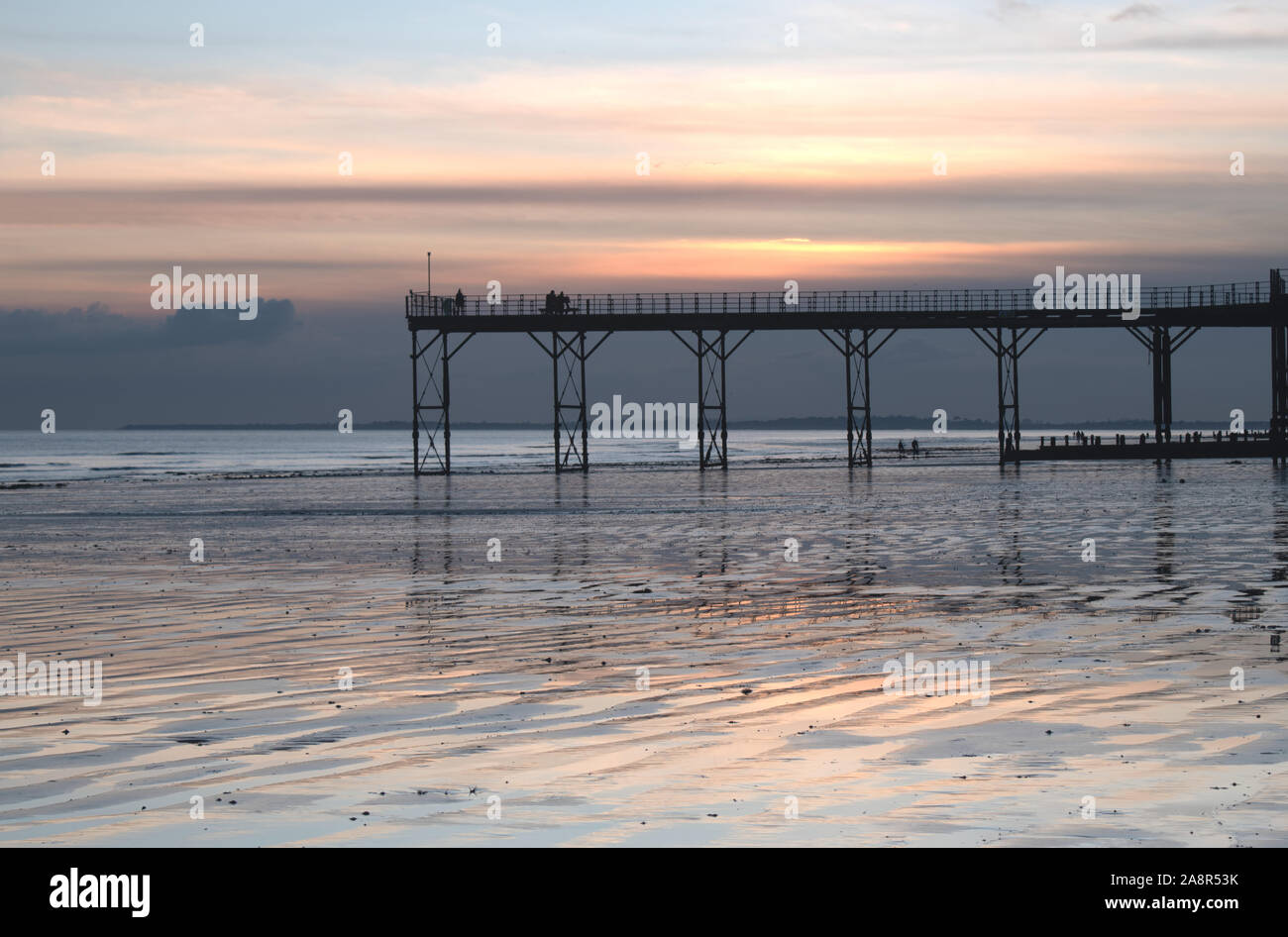 Historic old Pier in Bognor Regis West Sussex with a beautiful sunset behind and reflections on the sand at low tide. Stock Photo