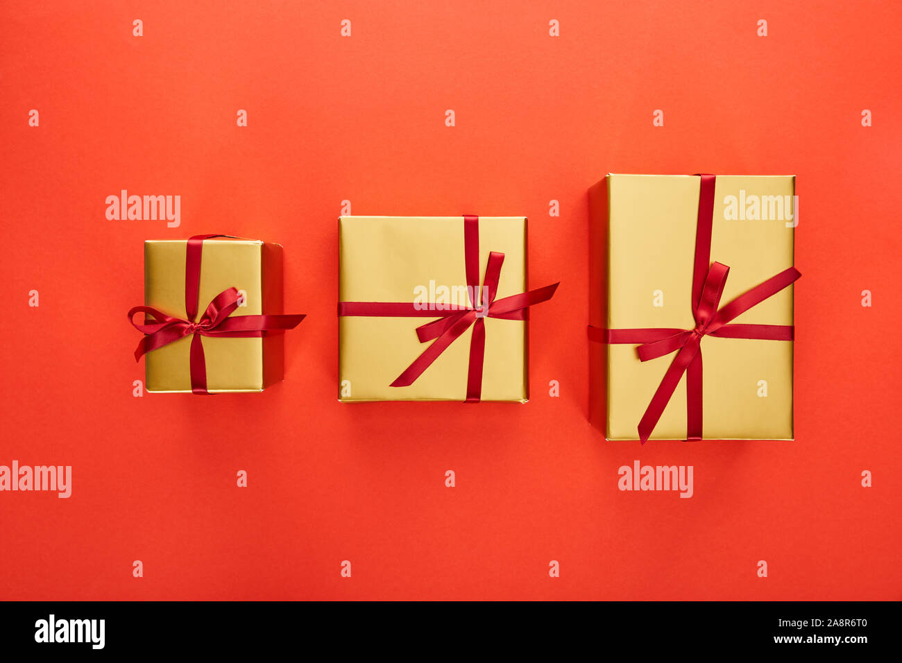 flat lay with three golden gift boxes on red background Stock Photo