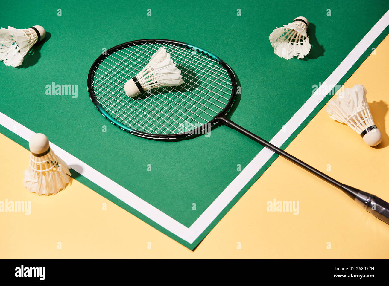 High angle view of badminton racket and shuttlecocks on green and yellow background Stock Photo