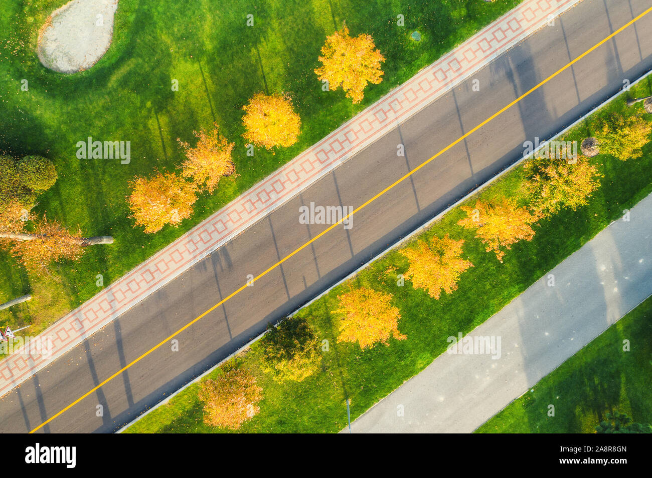 Aerial view of road through beautiful green field at sunset Stock Photo ...