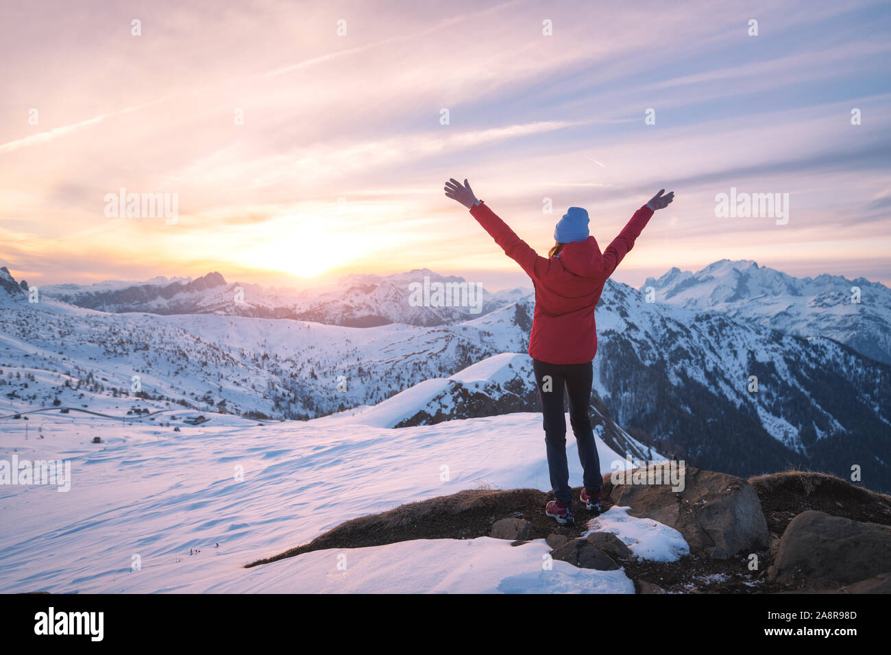Happy young woman in snowy mountains at sunset in winter Stock Photo