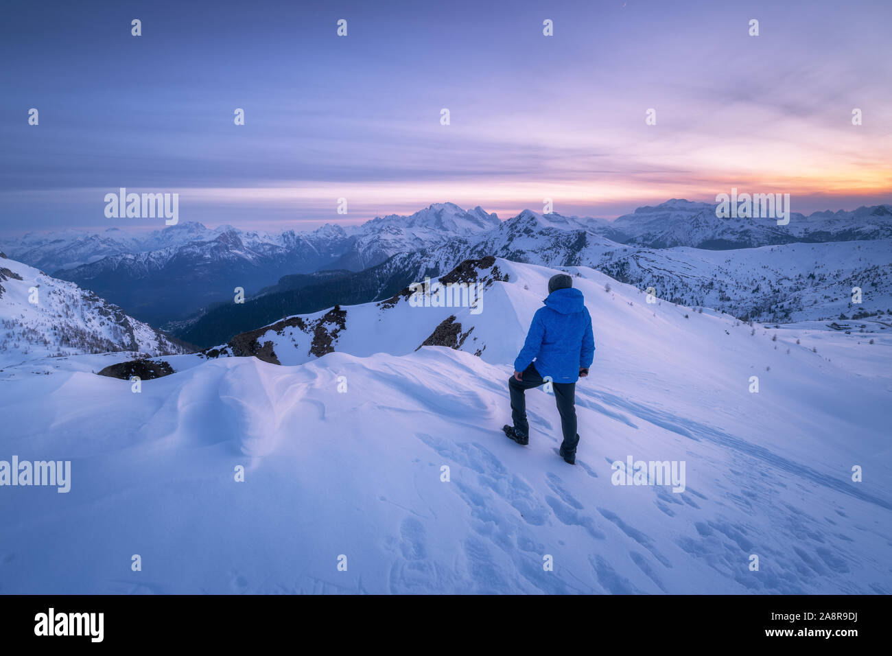 Young woman in snowy mountains at sunset in winter Stock Photo