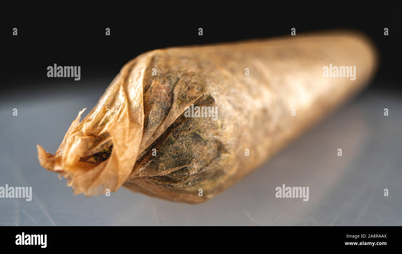 Cannabis flower joint in a brown hemp rolling paper. The flower inside is 9lb Hammer. A heavy indica leaning hybrid. Stock Photo