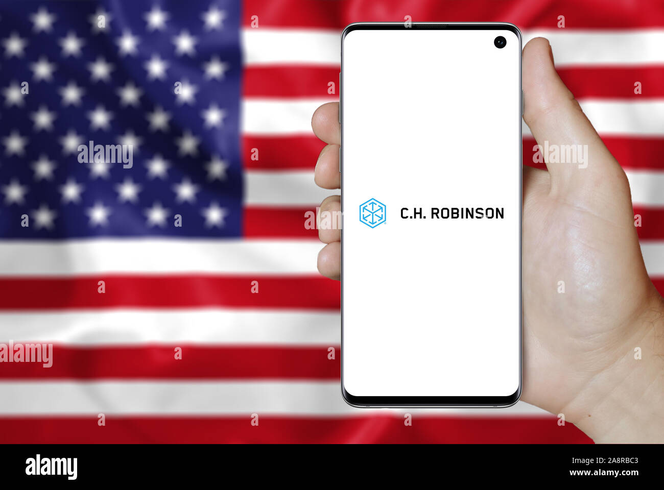 Logo of public company C. H. Robinson Worldwide displayed on a smartphone. Flag of USA background. Credit: PIXDUCE Stock Photo