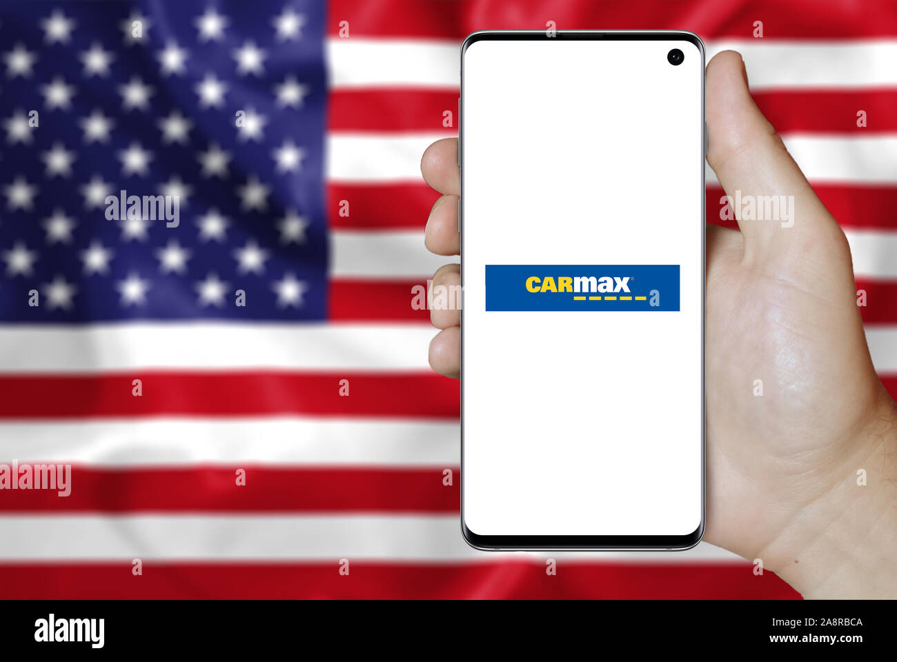 Logo of public company Carmax Inc displayed on a smartphone. Flag of