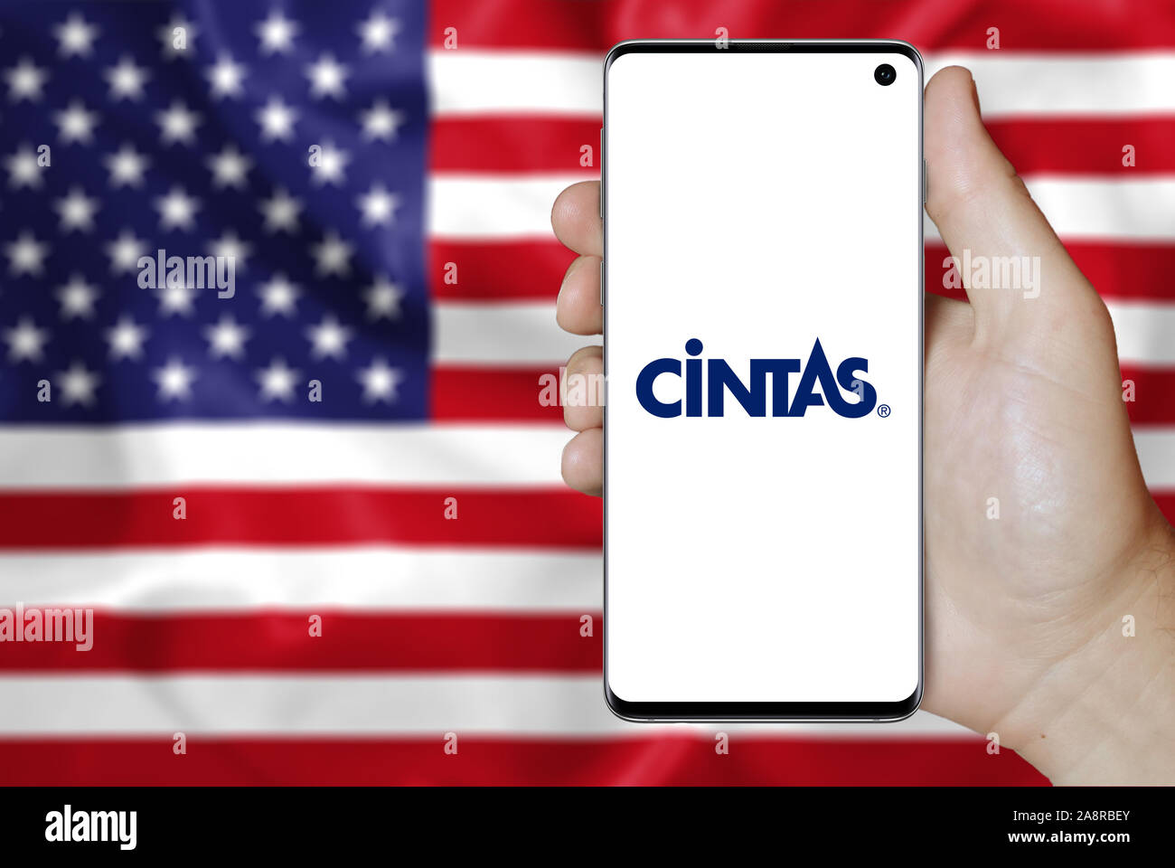 Logo of public company Cintas Corporation displayed on a smartphone. Flag of USA background. Credit: PIXDUCE Stock Photo