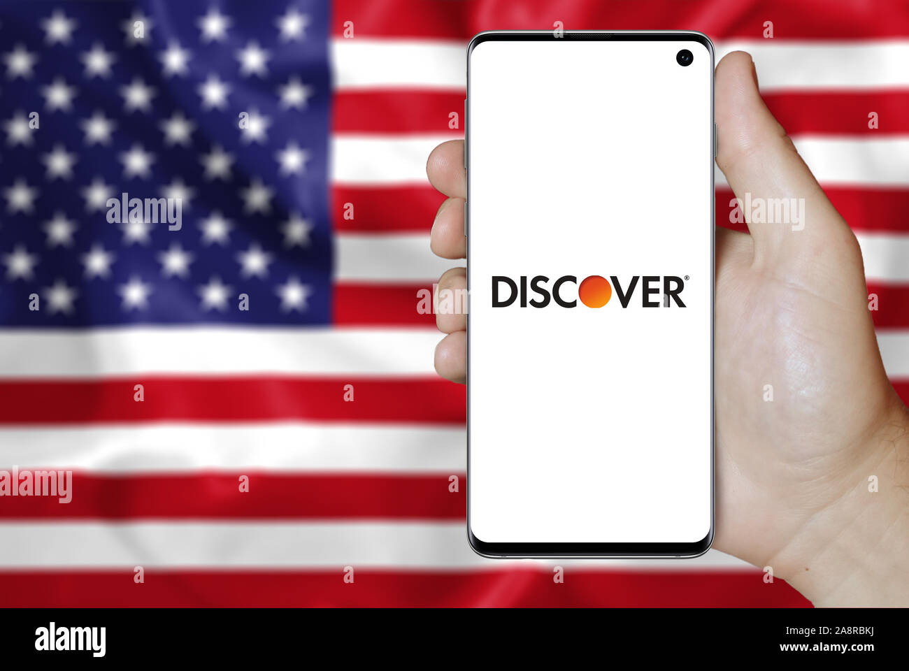 Logo of public company Discover Financial Services displayed on a smartphone. Flag of USA background. Credit: PIXDUCE Stock Photo