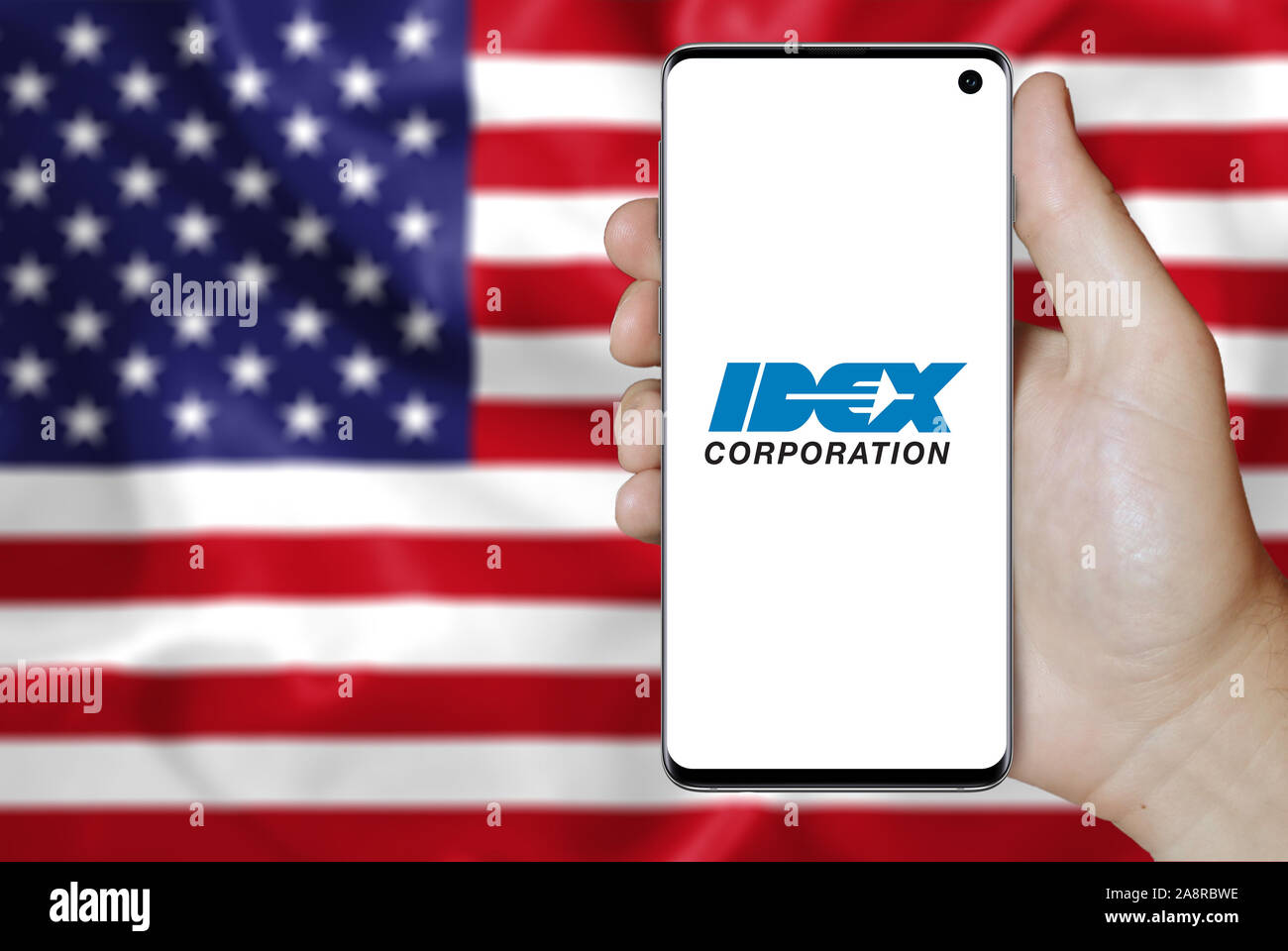 Logo of public company IDEX Corporation displayed on a smartphone. Flag of USA background. Credit: PIXDUCE Stock Photo