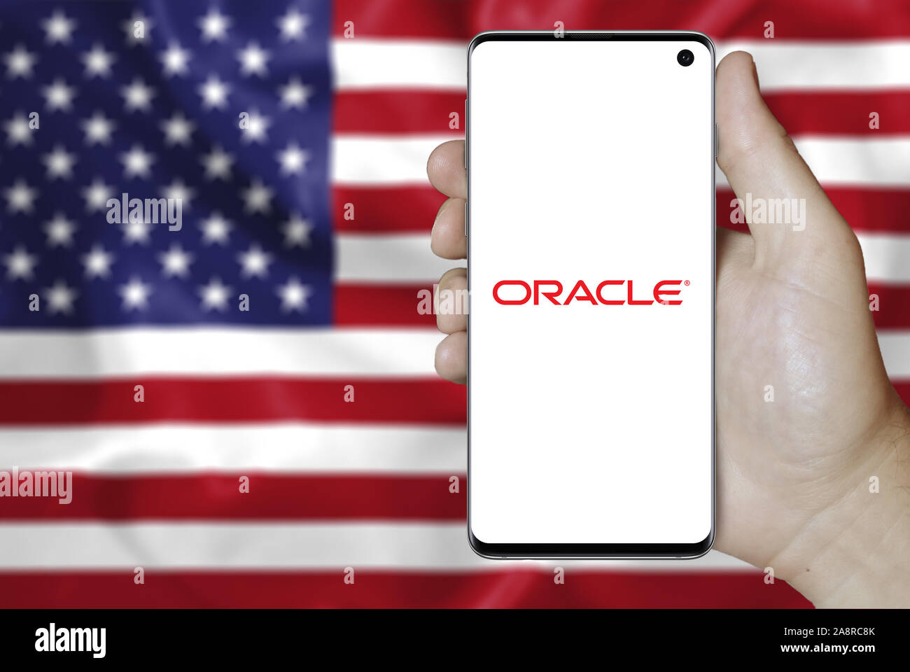 Logo of public company Oracle Corp. displayed on a smartphone. Flag of USA background. Credit: PIXDUCE Stock Photo