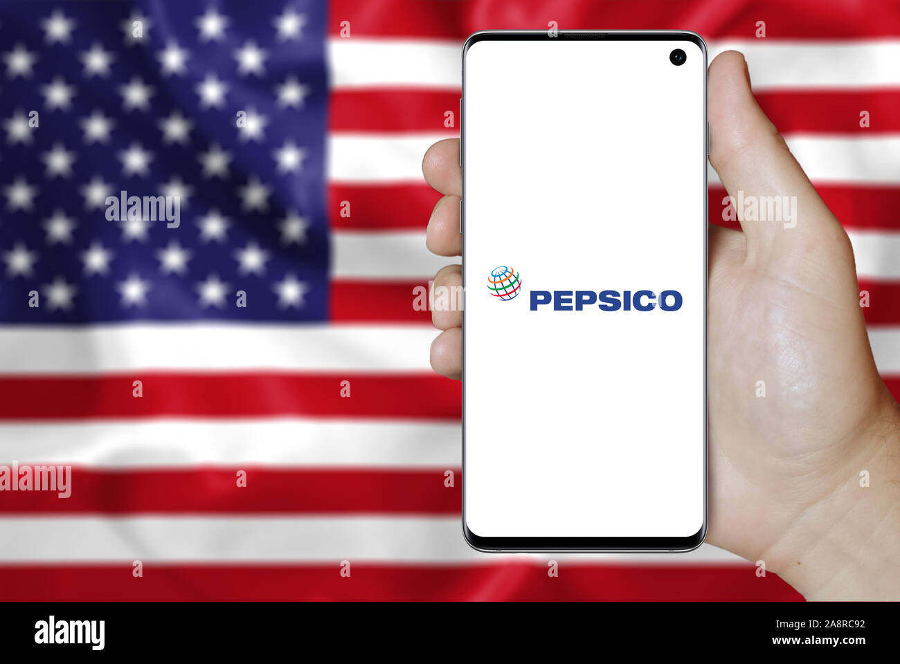 Logo of public company PepsiCo Inc. displayed on a smartphone. Flag of USA background. Credit: PIXDUCE Stock Photo