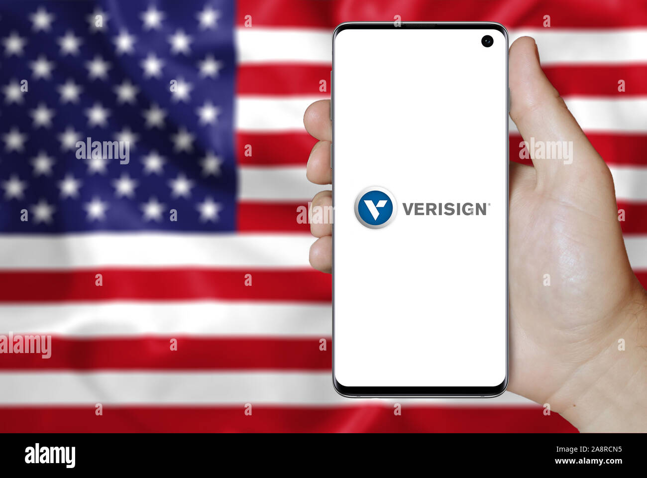 Logo of public company Verisign Inc. displayed on a smartphone. Flag of USA background. Credit: PIXDUCE Stock Photo