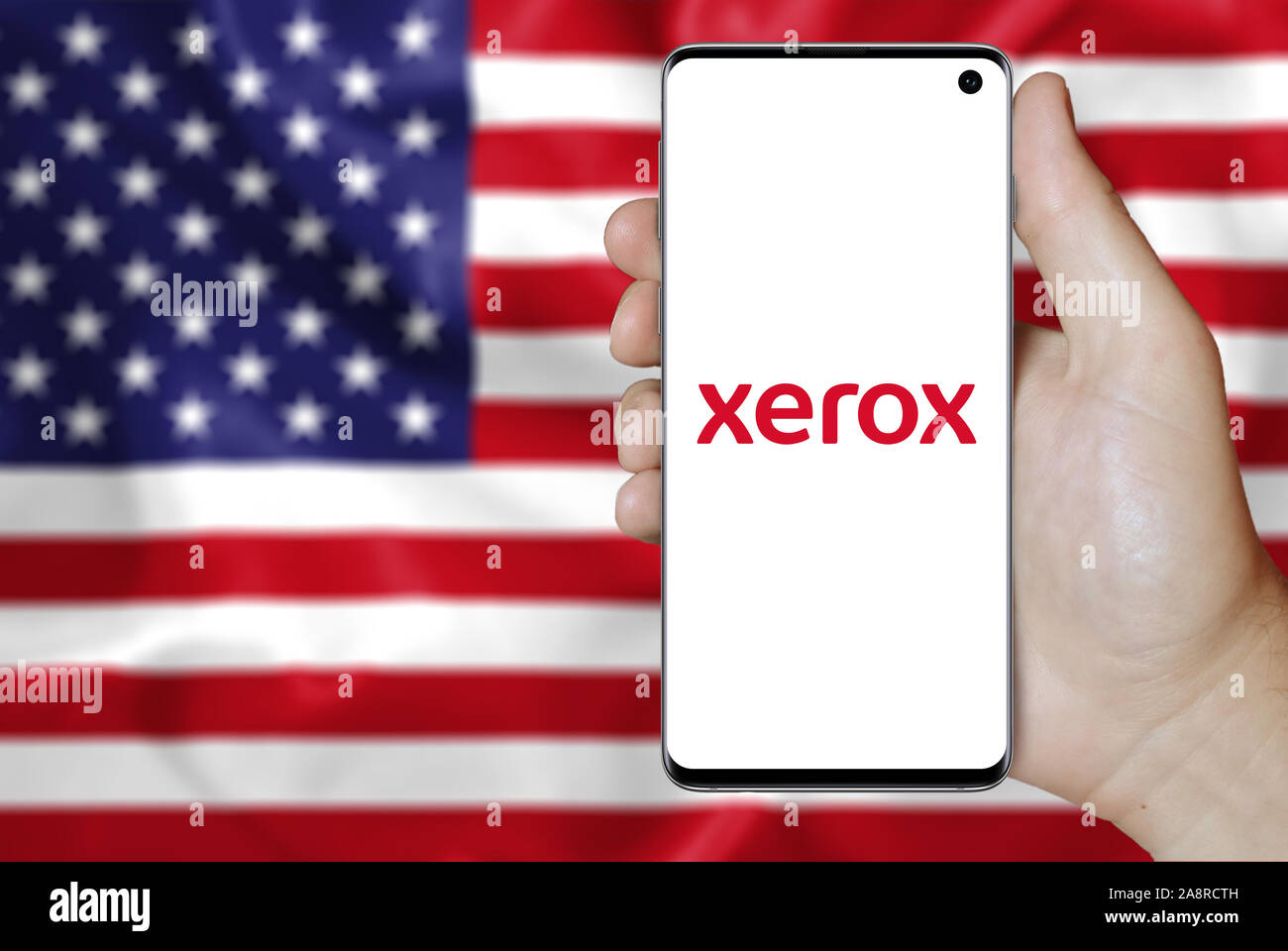 Logo of public company Xerox displayed on a smartphone. Flag of USA background. Credit: PIXDUCE Stock Photo