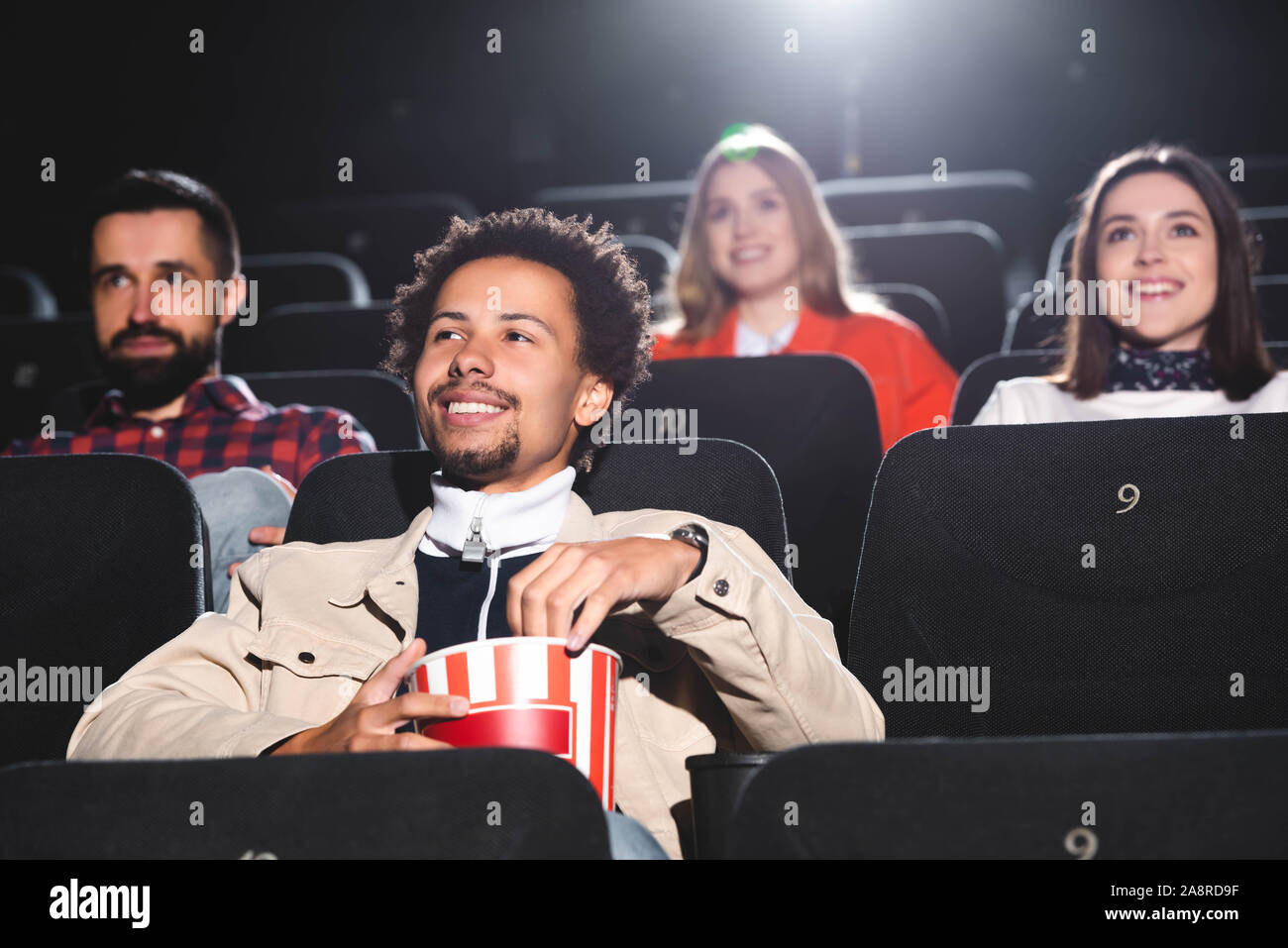 selective focus of smiling african american man holding popcorn and ...