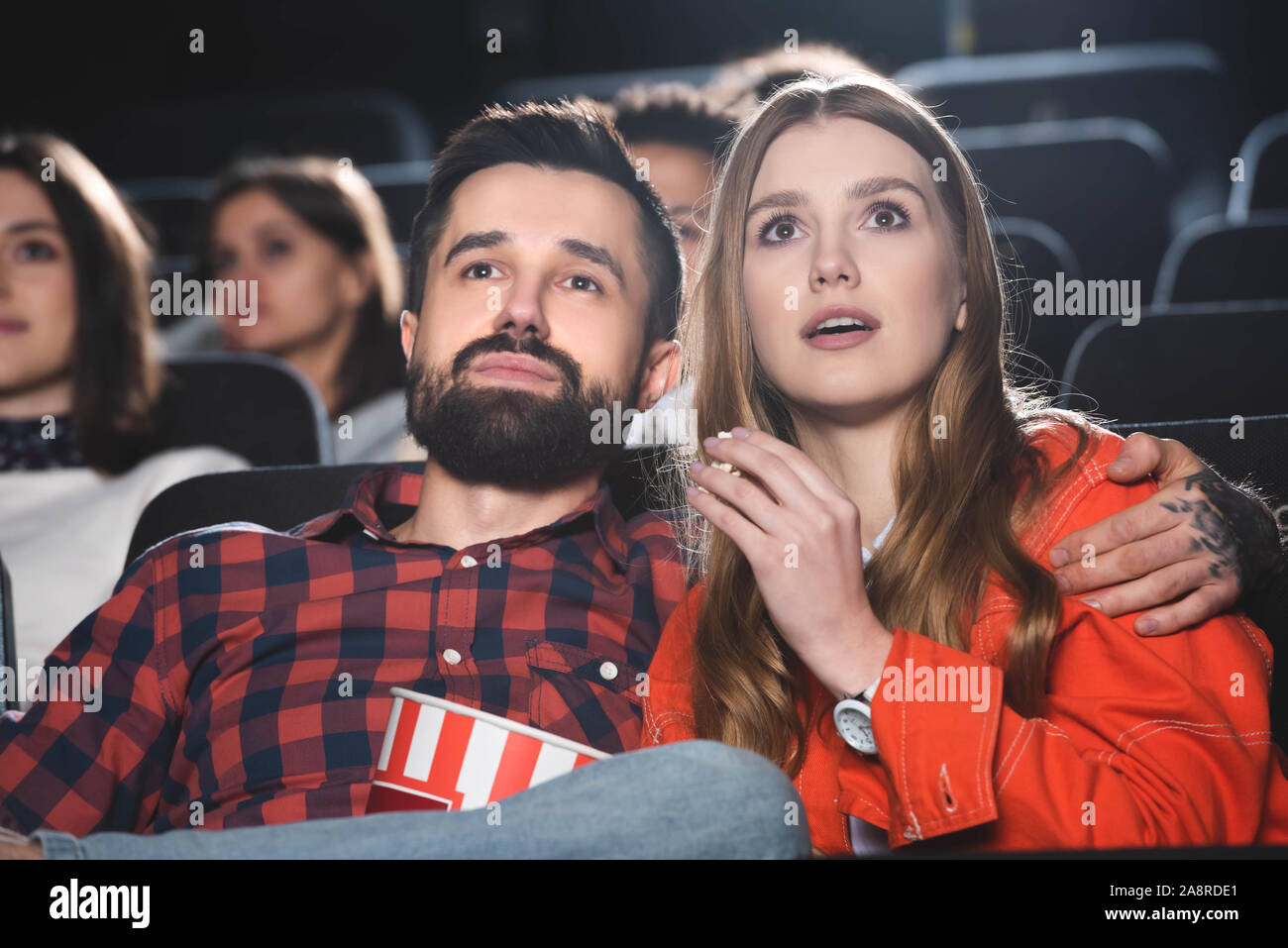 handsome boyfriend hugging shocked girlfriend and watching movie in ...