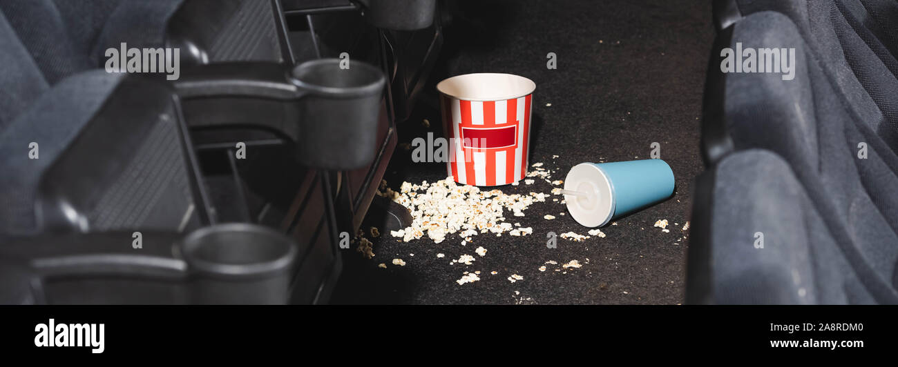 panoramic shot of popcorn and paper cup with soda on floor in cinema ...
