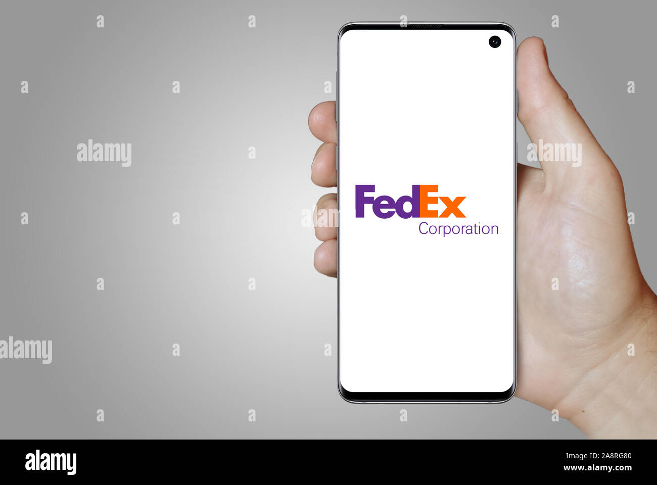 Logo of public company FedEx Corporation displayed on a smartphone. Grey background. Credit: PIXDUCE Stock Photo