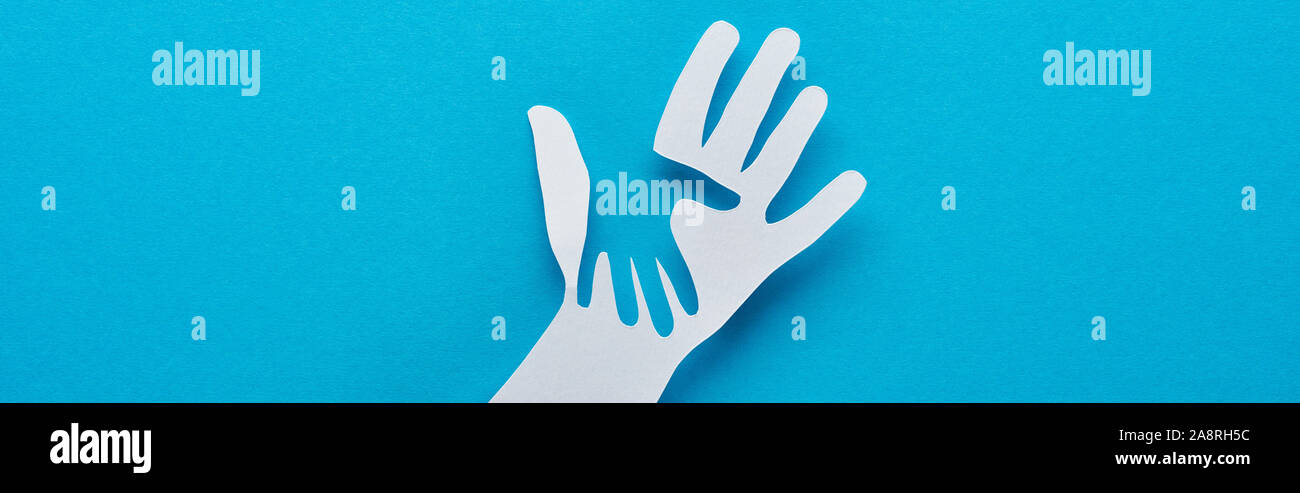 top view of paper cut parent and child hands on blue background ...