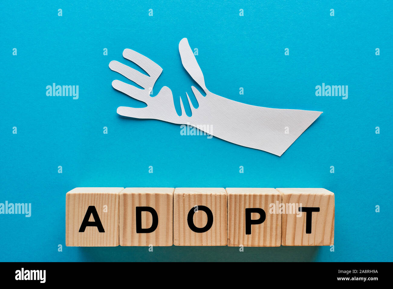 top view of paper cut parent and child hands and adopt lettering on ...