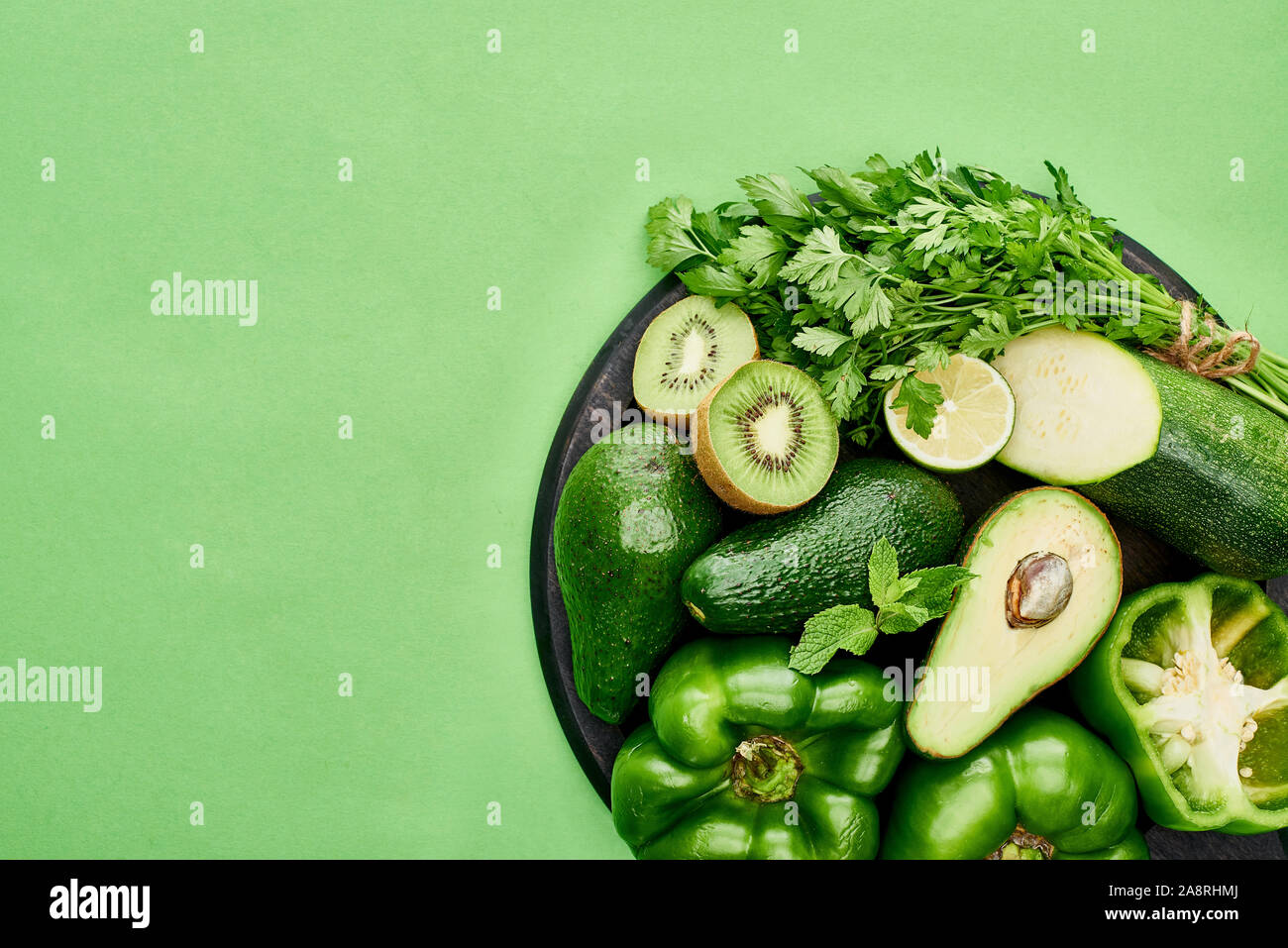 top view of avocados, peppers, kiwi, lime, zucchini and greenery on ...