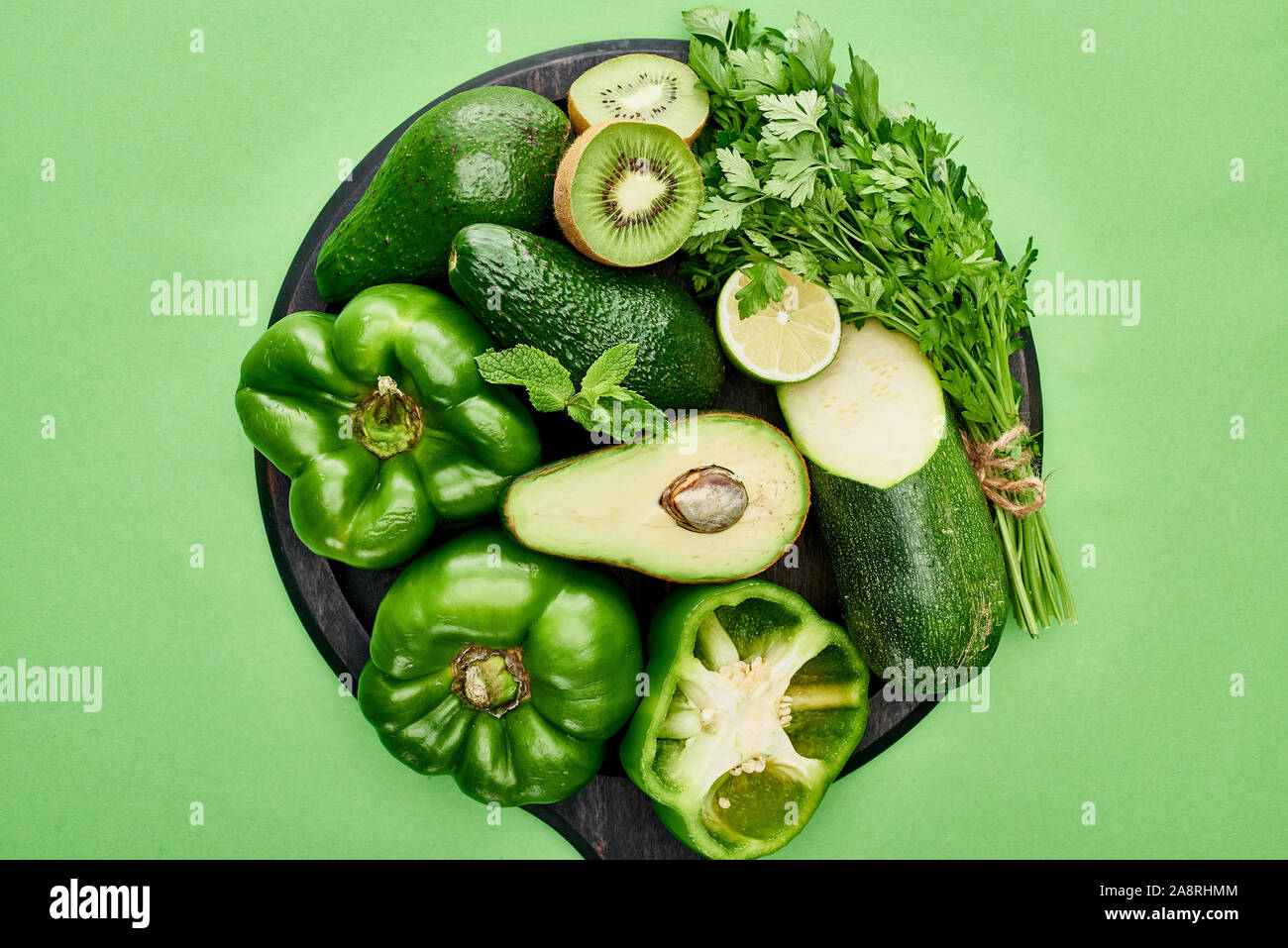 top view of avocados, peppers, kiwi, lime, zucchini and greenery on ...