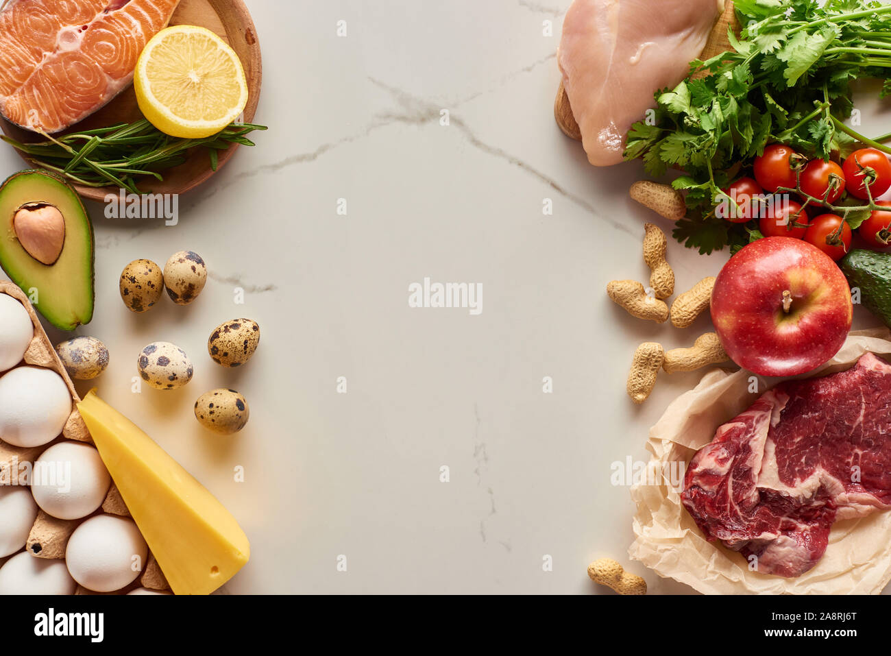 Top view of raw meat, poultry and fish with eggs, avocado, lemon