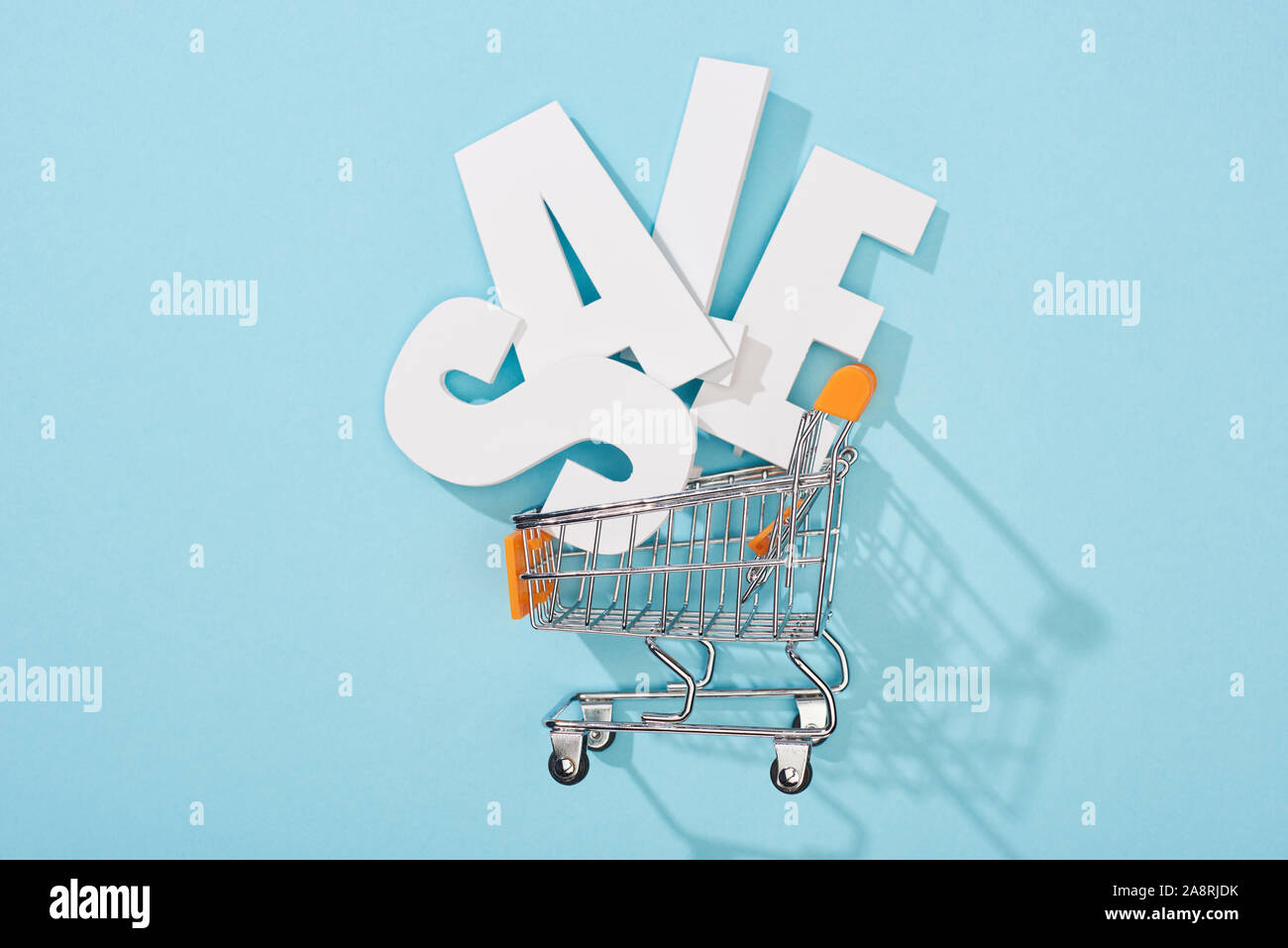top view of white sale lettering in decorative shopping cart on blue ...