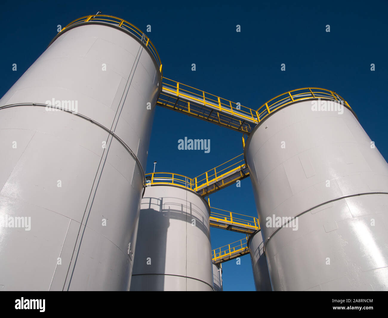 Oil storage tanks / silos against a clear blue sky. Stock Photo