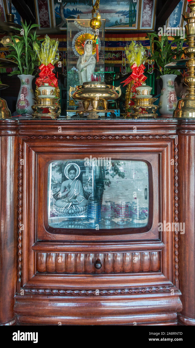 Nha Trang, Vietnam - March 11, 2019: Inside Farm house. Old brown wooden TV-cabinet refurbished into small altar with Buddhia photo and Guan Yin statu Stock Photo