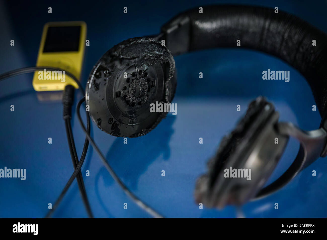Too loud: burned headphones attached to a personal music player. Low key  Stock Photo - Alamy