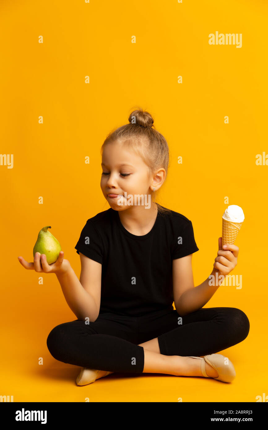 playful little gymnast choosing between punching bag and ice cream Stock Photo