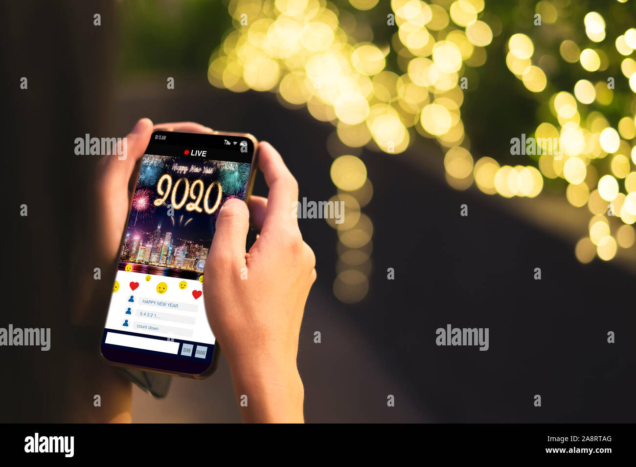 Woman Hand holding mobile see live streaming countdown to Happy new year 2020 with fireworks over cityscape on screen with light bokeh background,Digi Stock Photo