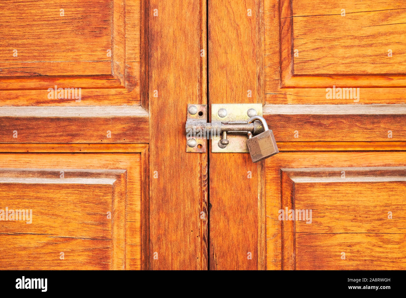 Beautiful timber door locked up with a bolt and a padlock. Stock Photo