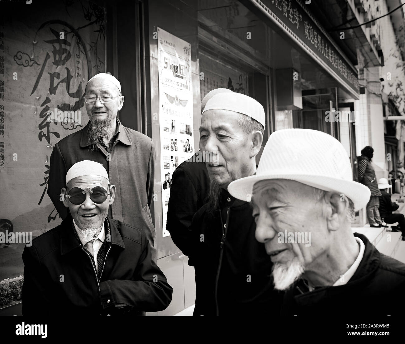 Carefree Hui men watch ongoing bargaining at the streets of the Islamic Quarter, Xining, China Stock Photo