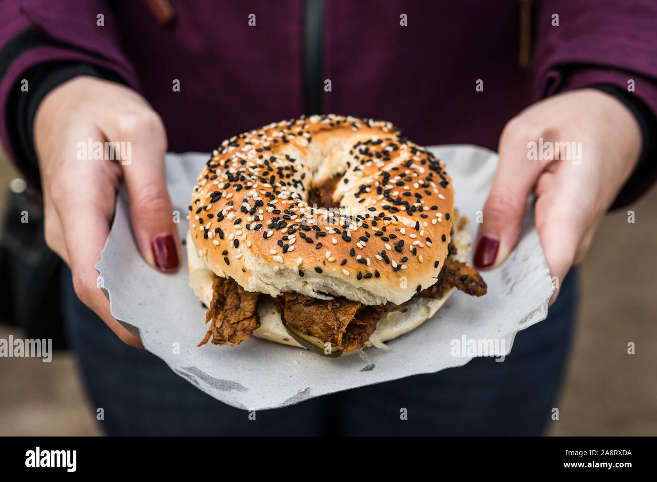 Bagel with pastrami beef meat and pickles at a street food market Stock