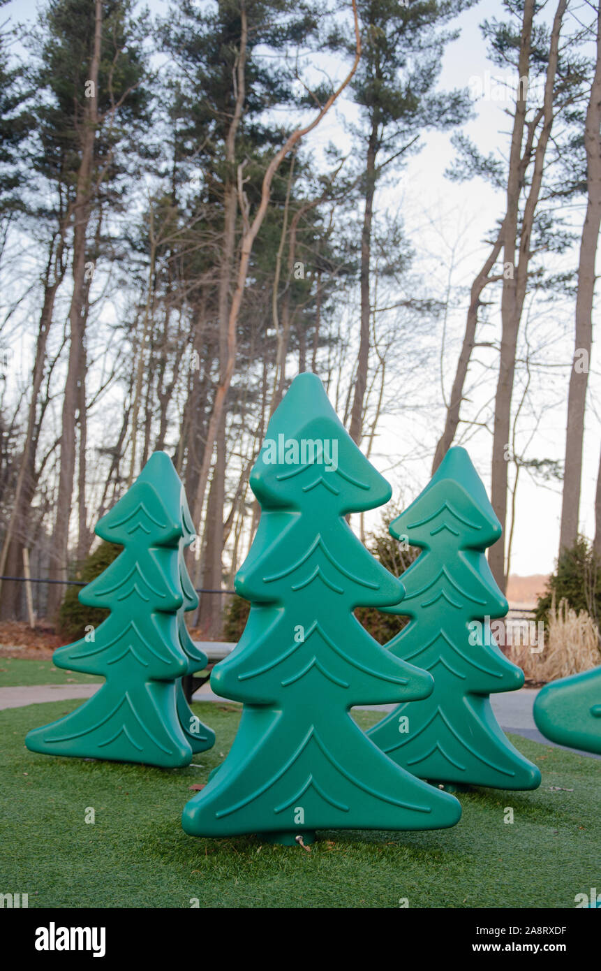 Fake plastic trees on a playground stand in front of real trees Stock
